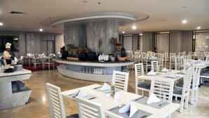 Un restaurant amb un mostrador central, caires blanques i taules preparades per dinar.