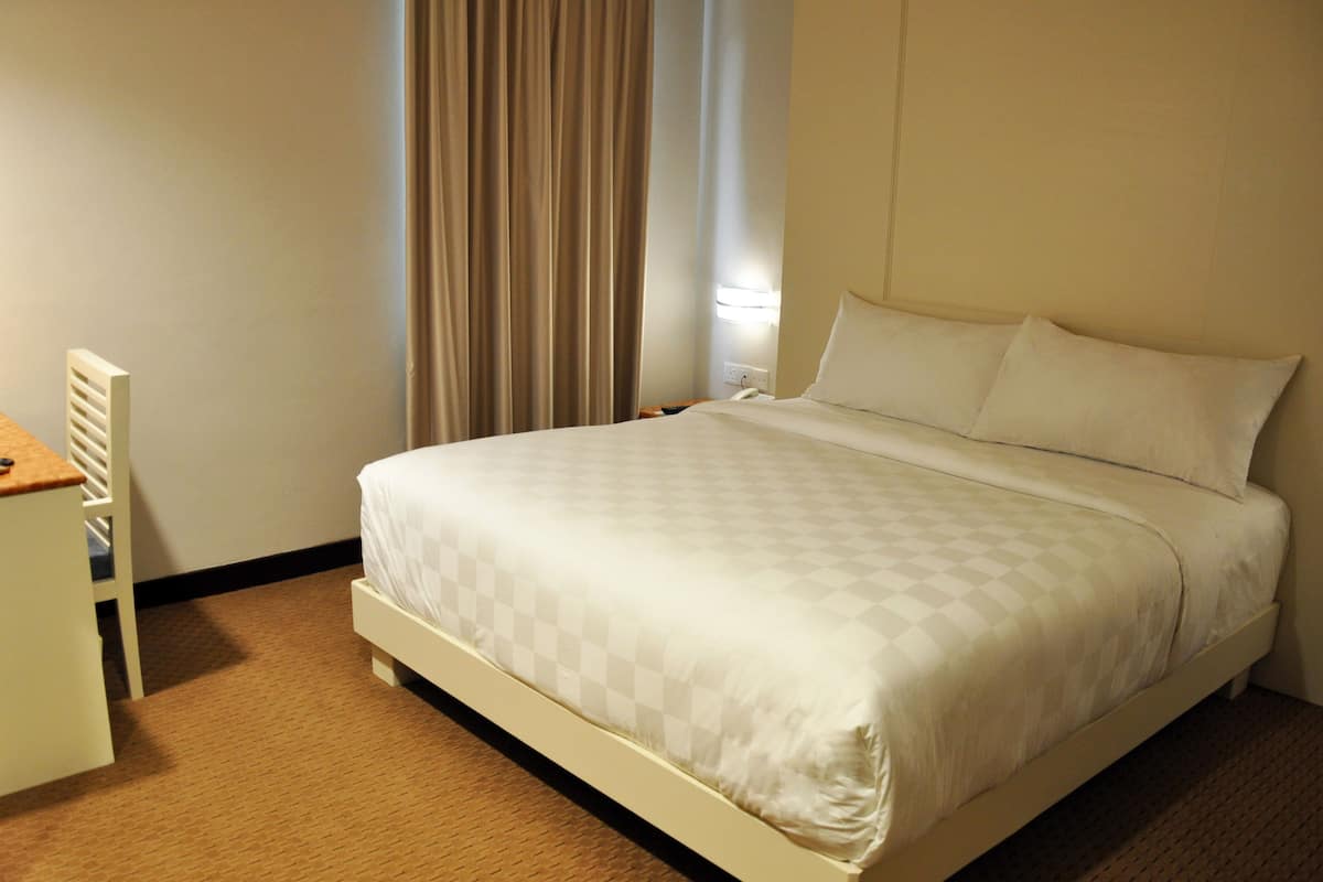 Une chambre d’hôtel avec un lit, un bureau et une fenêtre avec des rideaux.