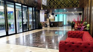 Un hall d'hotel amb un sofà vermell, una recepció i un gran vidrier d'entrada.