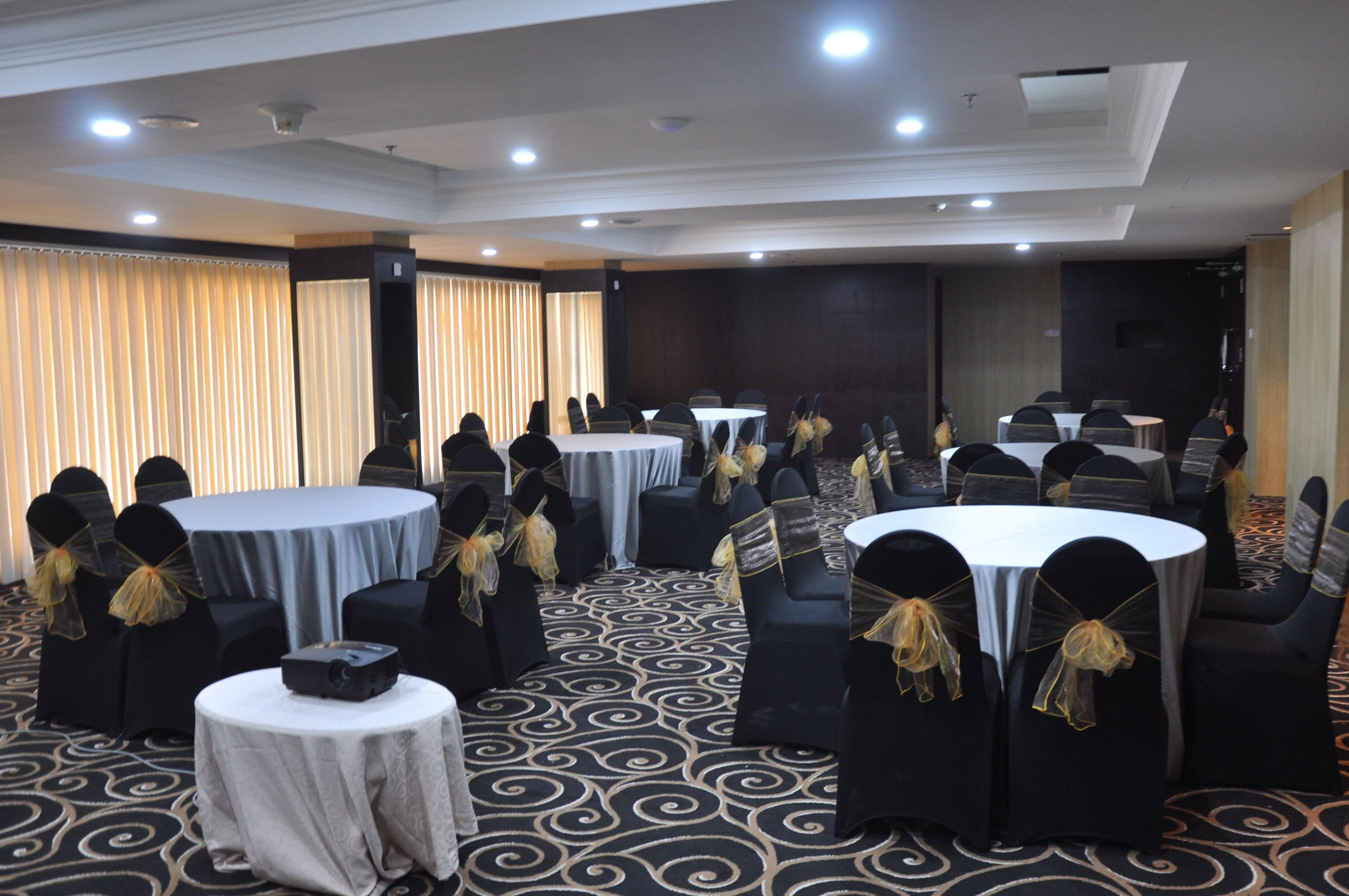 A conference room with round tables and chairs, a projector on one table, and a patterned carpet.