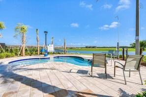 Relax by the serene pool surrounded by lush greenery and lounge chairs.