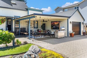 A covered patio with outdoor furniture, a grill, and a painting of a vehicle.