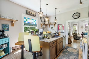 A kitchen with a central island, pendant lights, and a clock on the wall.