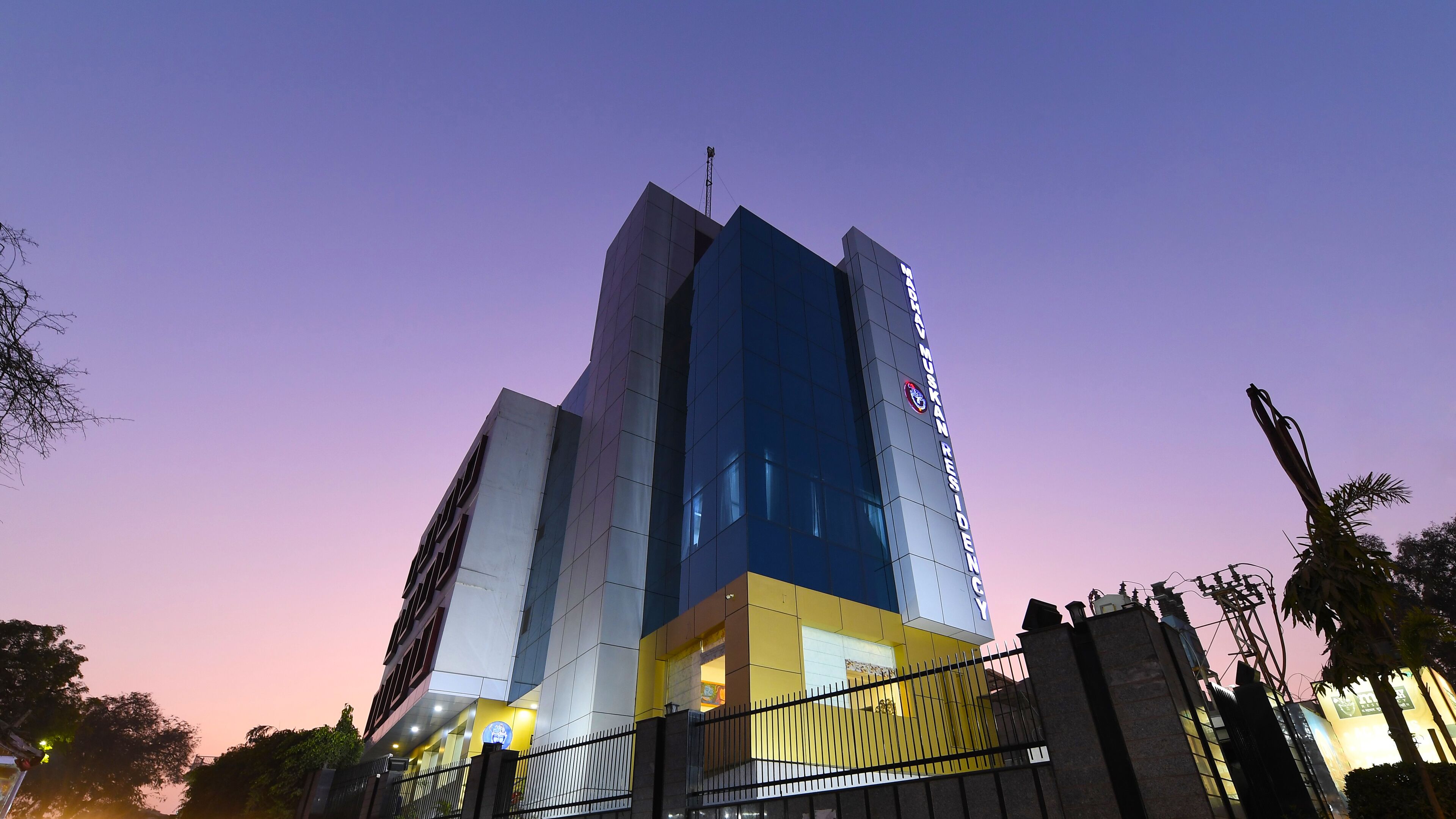 A modern building with a prominent entrance and a sign indicating it is a hotel.