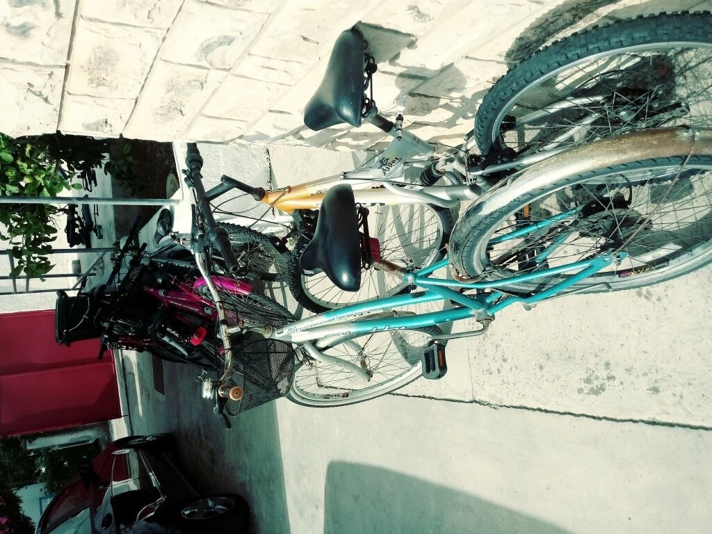 A bicycle parked on a concrete surface with a metal rack attached to a building.