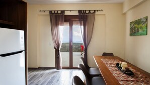 Une cuisine équipée d’un réfrigérateur, d’une table à manger avec des chaises, et offrant une vue sur un paysage montagneux grâce à une porte vitrée.
