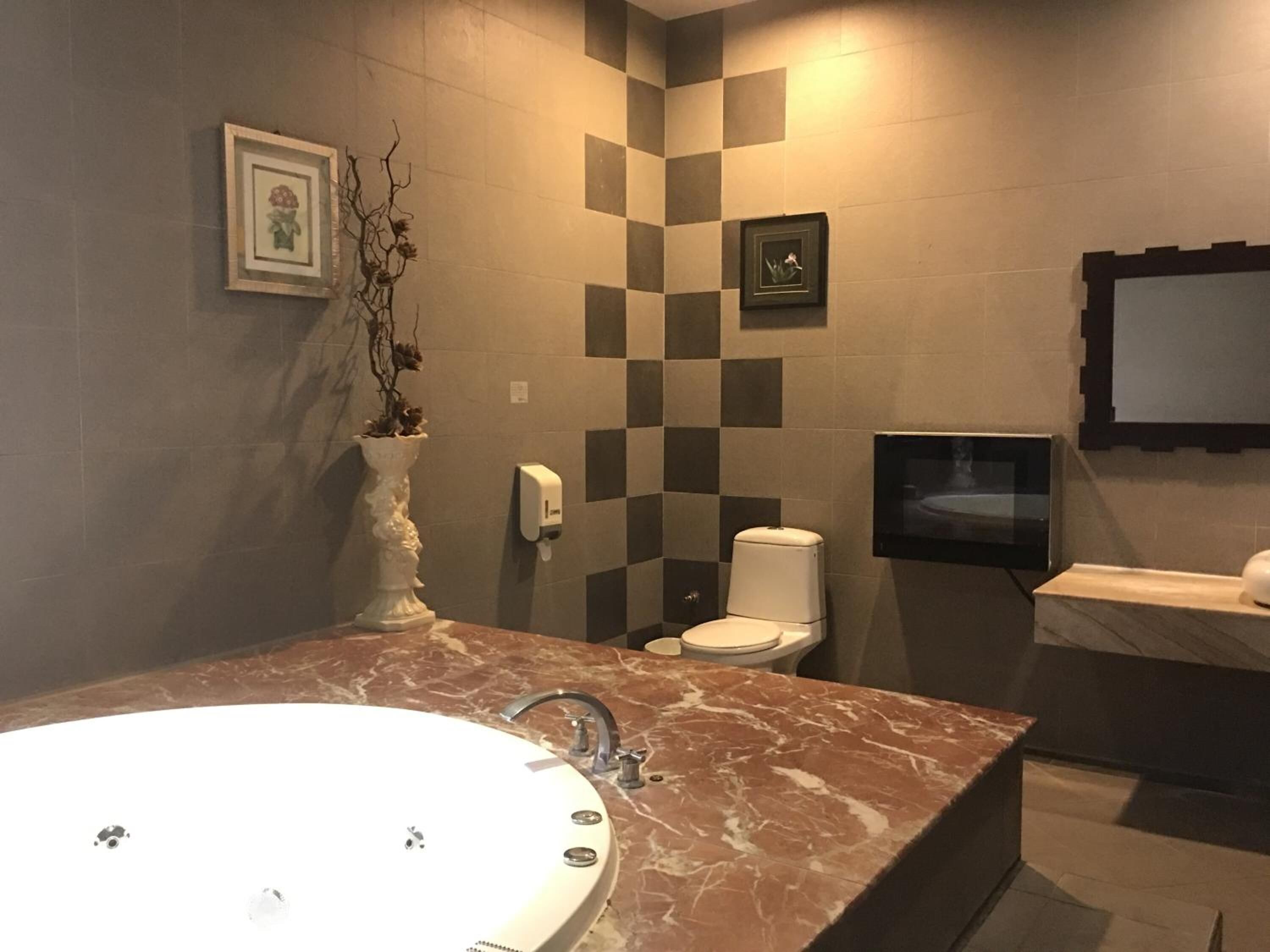 A bathroom with a marble sink, a toilet, a hand dryer, and framed pictures on the wall.