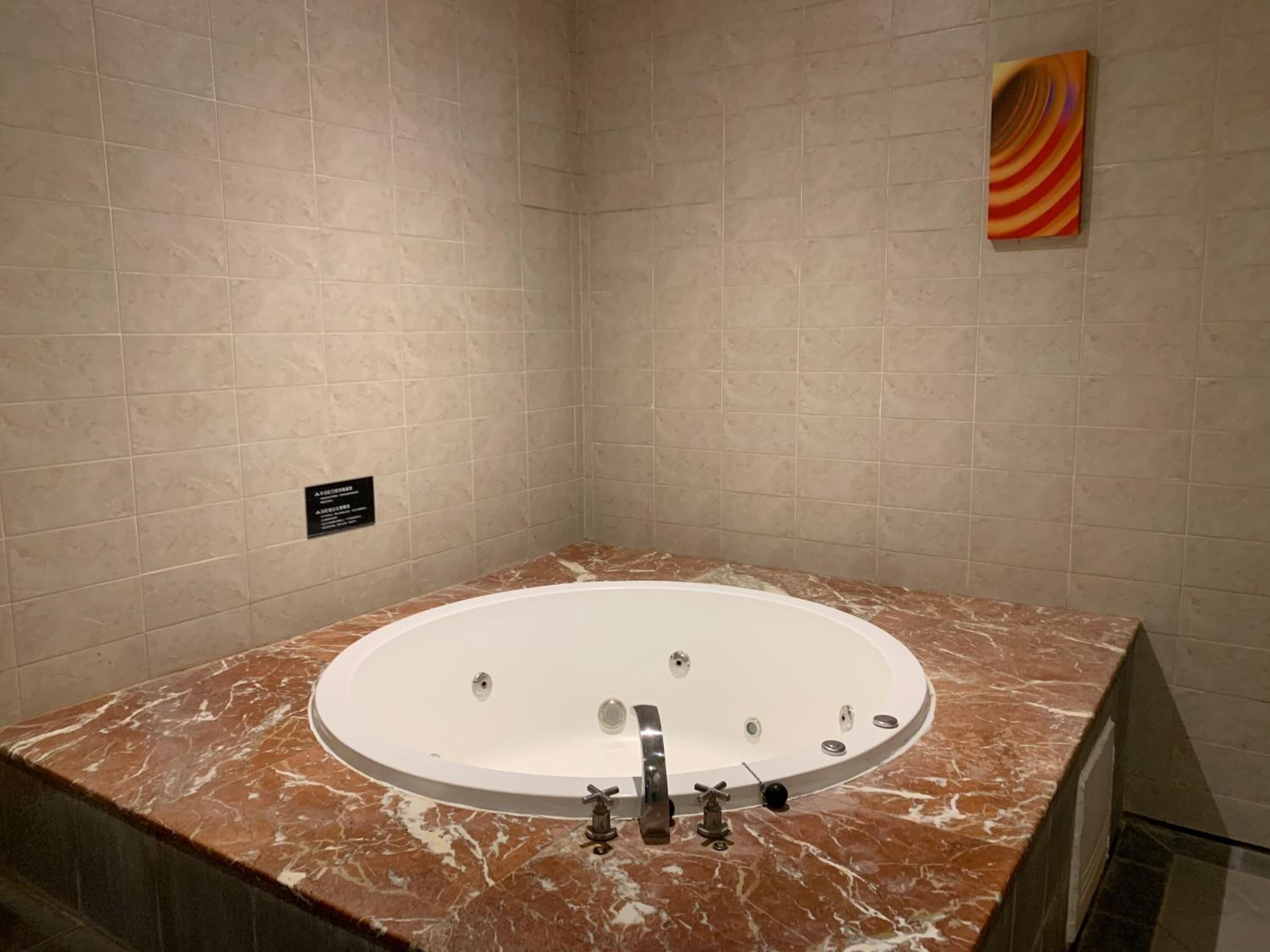A modern bathroom with a freestanding bathtub, marble countertops, and a tiled wall.