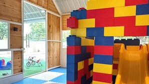 Un espace de jeux avec une piscine à balles, des blocs de mousse colorés et un toboggan.