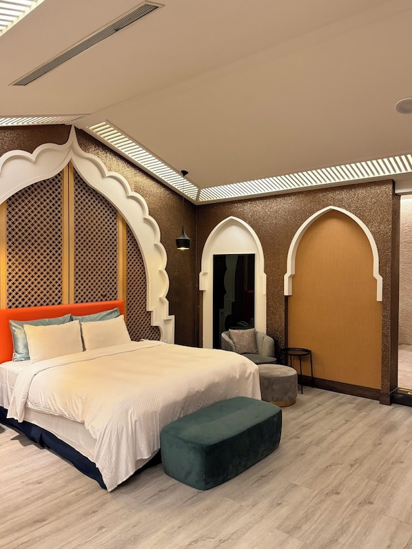 A modern bedroom with a large bed, a bench, and decorative arches.