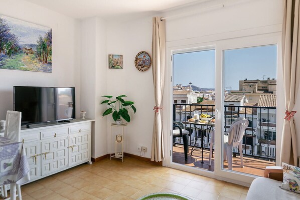 Un appartement moderne doté d’un balcon, d’une télévision, d’une table à manger et d’une plante.