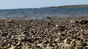 En stenstrand med fri utsikt över havet och det avlägsna landskapet.