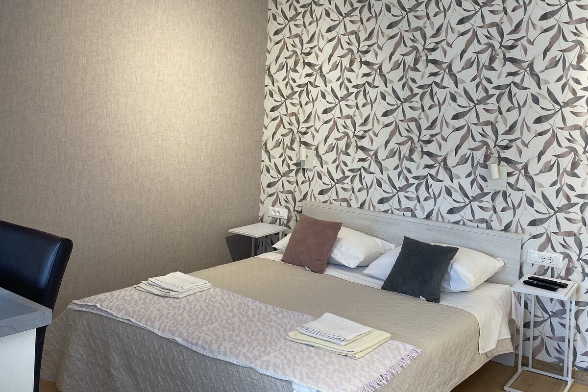 A modern hotel room with a large bed, a desk, and a chair.
