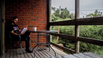 A person sitting at a table on a wooden deck with a brick wall behind them.