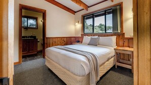 Une chambre avec un grand lit, une tête de lit en bois, une fenêtre avec vue et une table de chevet en bois.