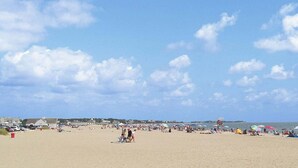 Une plage bondée, avec des parasols et beaucoup de monde.