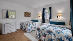 Une chambre d’hôtel avec deux lits, une commode, un miroir et deux lampes fixées au mur.