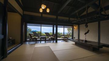 A room with tatami mats, wooden furniture, and a view of the sea.