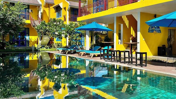 A hotel with a pool, multiple balconies, and outdoor seating areas. - Chez Mimosa Hoi An - Rice Field Retreat (Da Nang)
