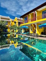 Un hotel con piscina, varios balcones y zonas de estar al aire libre.