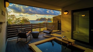 A balcony with wooden flooring, two rocking chairs, a small wooden table, and a hot tub. - Mayu Futahari (Nishiizu)