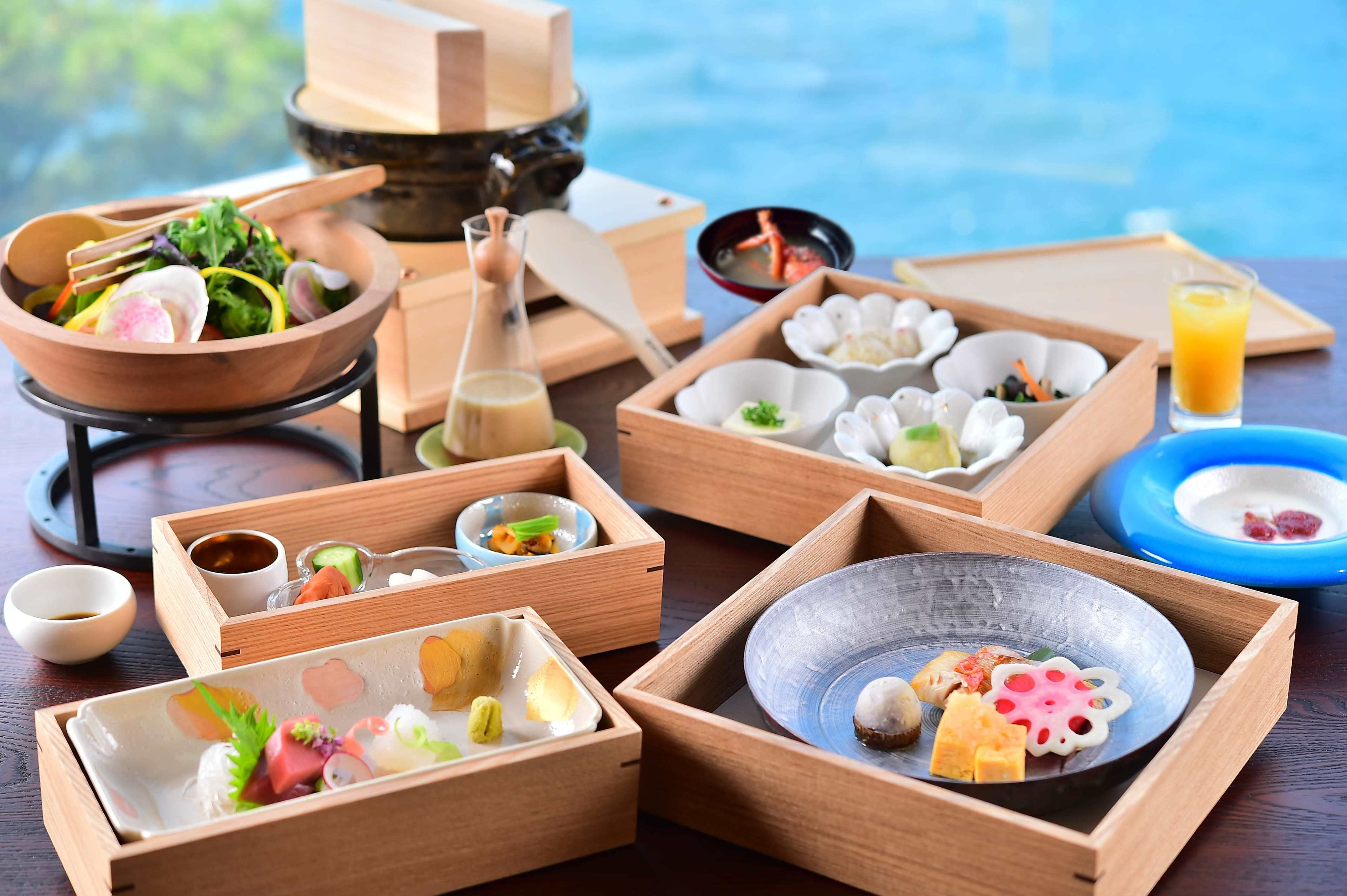 A traditional Japanese meal setup with various dishes and utensils on wooden trays.