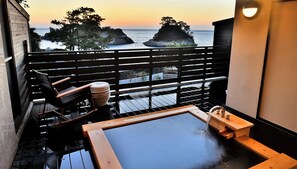 A balcony with a hot tub, wooden furniture, and a view of the sea at sunset. - Mayu Futahari (Nishiizu)