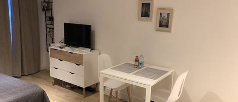 Un dormitorio con una cama, un escritorio con computadora, un televisor y dos cuadros en la pared.