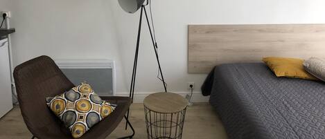 A bedroom with a bed, a chair, a floor lamp, and wall art.