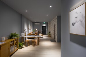 A modern interior with a dining area, a sofa, and a wall-mounted horse painting. - Mr Nordic Inn (Hualien City)