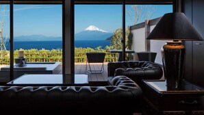 A modern room with a view of a mountain and sea, featuring a sofa, a table, and a lamp. - Fugaku Gunjo (Izu)