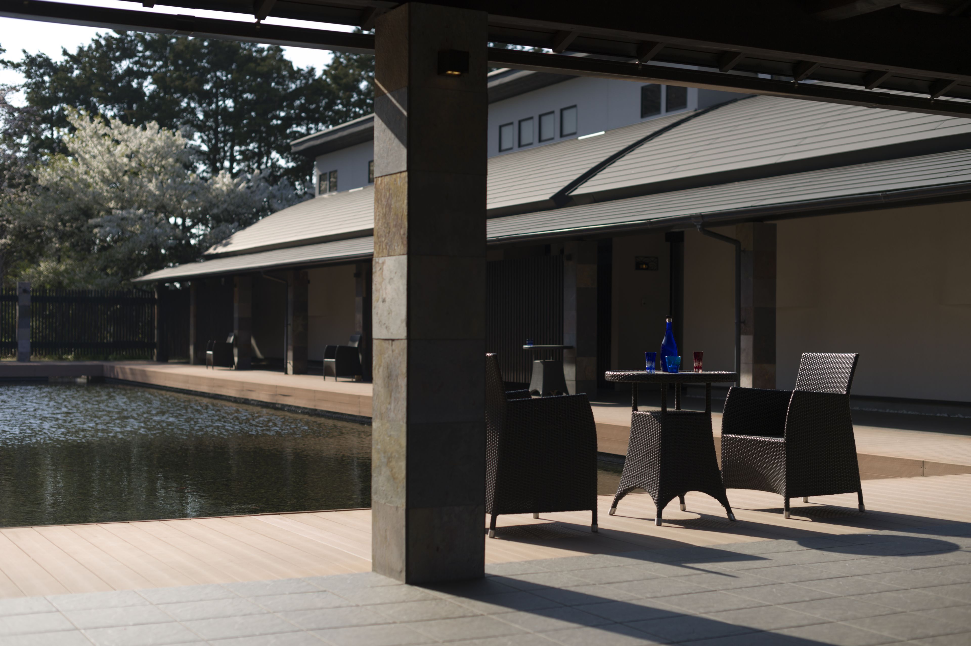 An outdoor patio area with a pool, seating, and a covered section with tables and chairs.