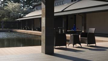 An outdoor patio area with a pool, seating, and a covered section with tables and chairs.