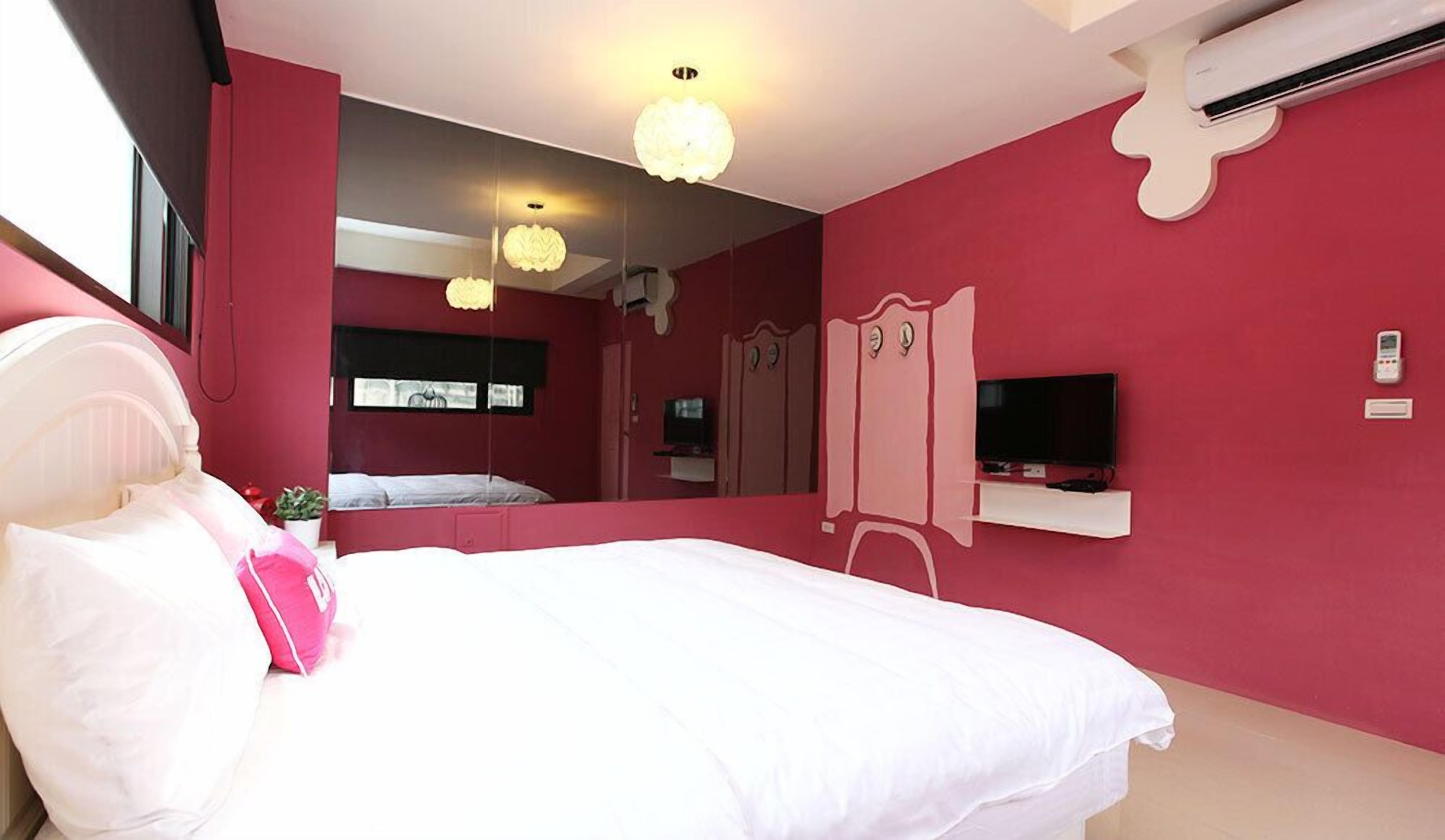 A bedroom with a bed, a TV, a mirror, and a wardrobe.