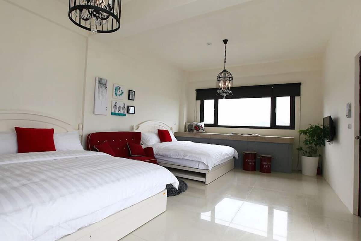A bedroom with two beds, a window, and a ceiling light fixture.