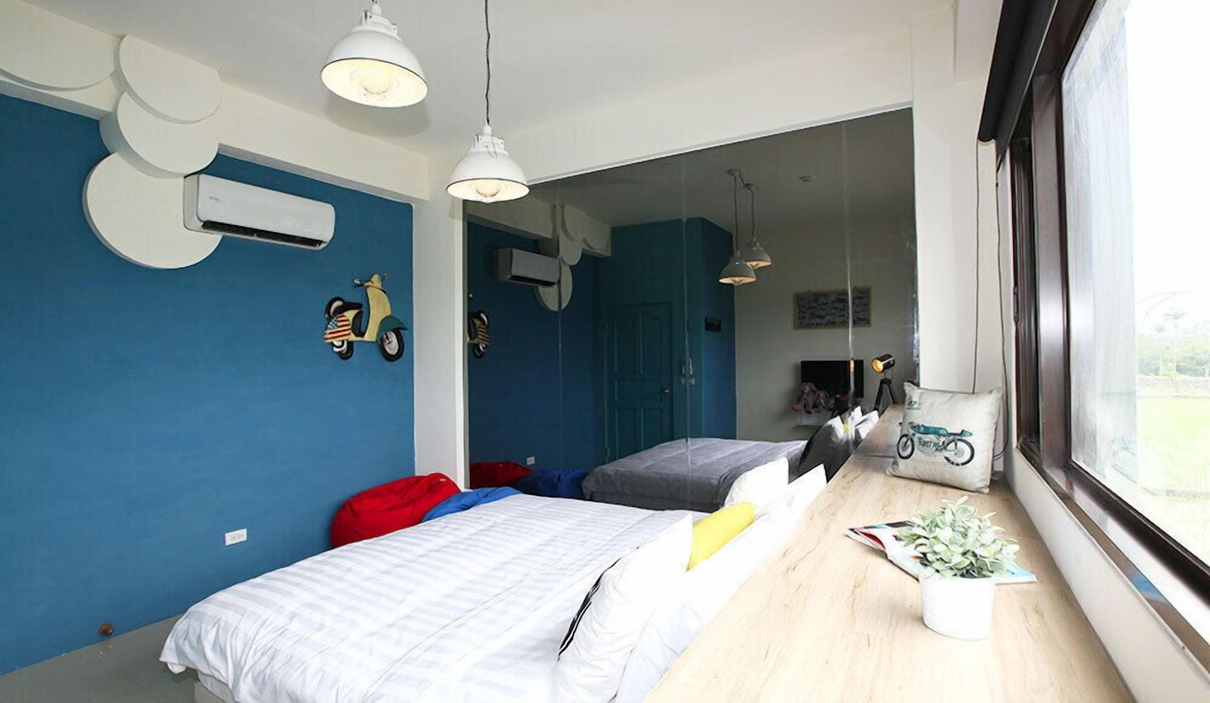 A modern bedroom with two beds, a large window, and a view of the outdoors.