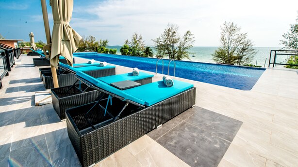 A poolside area with lounge chairs and a view of the sea. - Hai Ma Hotel (Sihanoukville)