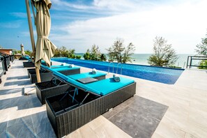 A poolside area with lounge chairs and a view of the sea.