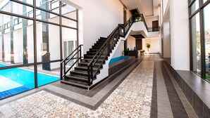 A modern interior with a central staircase, large windows, and a patterned floor. - Hai Ma Hotel (Sihanoukville)