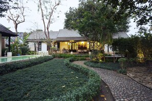 Relax in a serene outdoor space with a beautifully manicured lawn, stone pathway, and lush greenery.