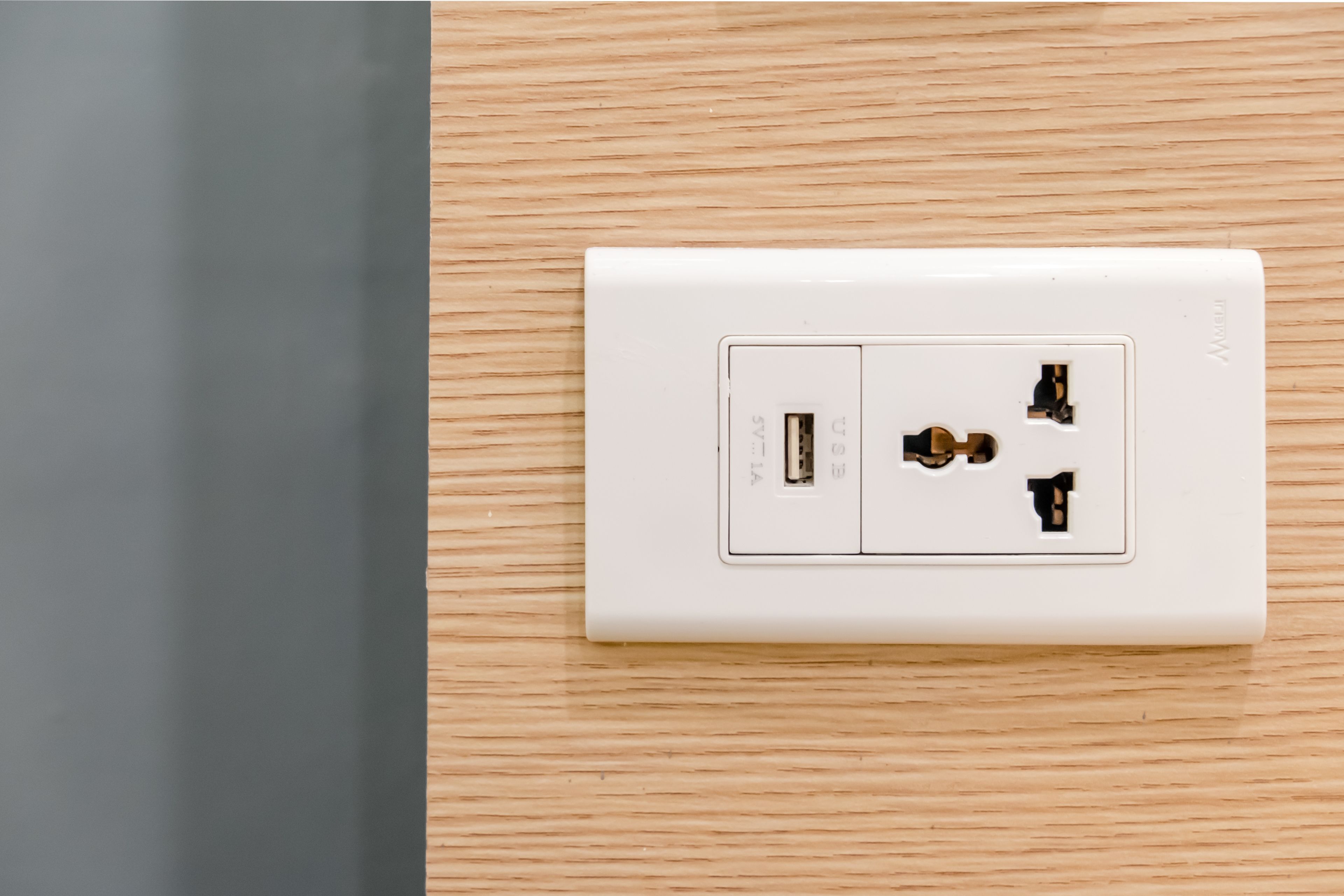 A white electrical outlet on a wooden wall.