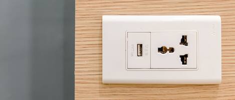 A white electrical outlet on a wooden wall.