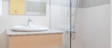 Un baño moderno con cabina de ducha de vidrio, un lavabo con espejo y un perchero para toallas.