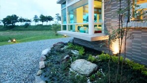 Een modern huis met een groot raam, een pad van stenen en een verzorgde tuin.