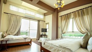 Een slaapkamer met twee bedden, een televisie en een groot raam met gordijnen.