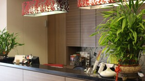A kitchen counter with a potted plant, a white vase, and a red and white patterned lamp. - Home Full Hotel (Jincheng)