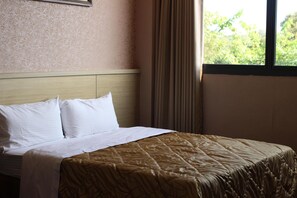 A neatly made bed with white linens and a patterned bedspread, a headboard, and a window with curtains. - Home Full Hotel (Jincheng)