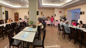 A dining area with tables and chairs, a pillar, and a butterfly decoration on the wall. - Home Full Hotel (Jincheng)