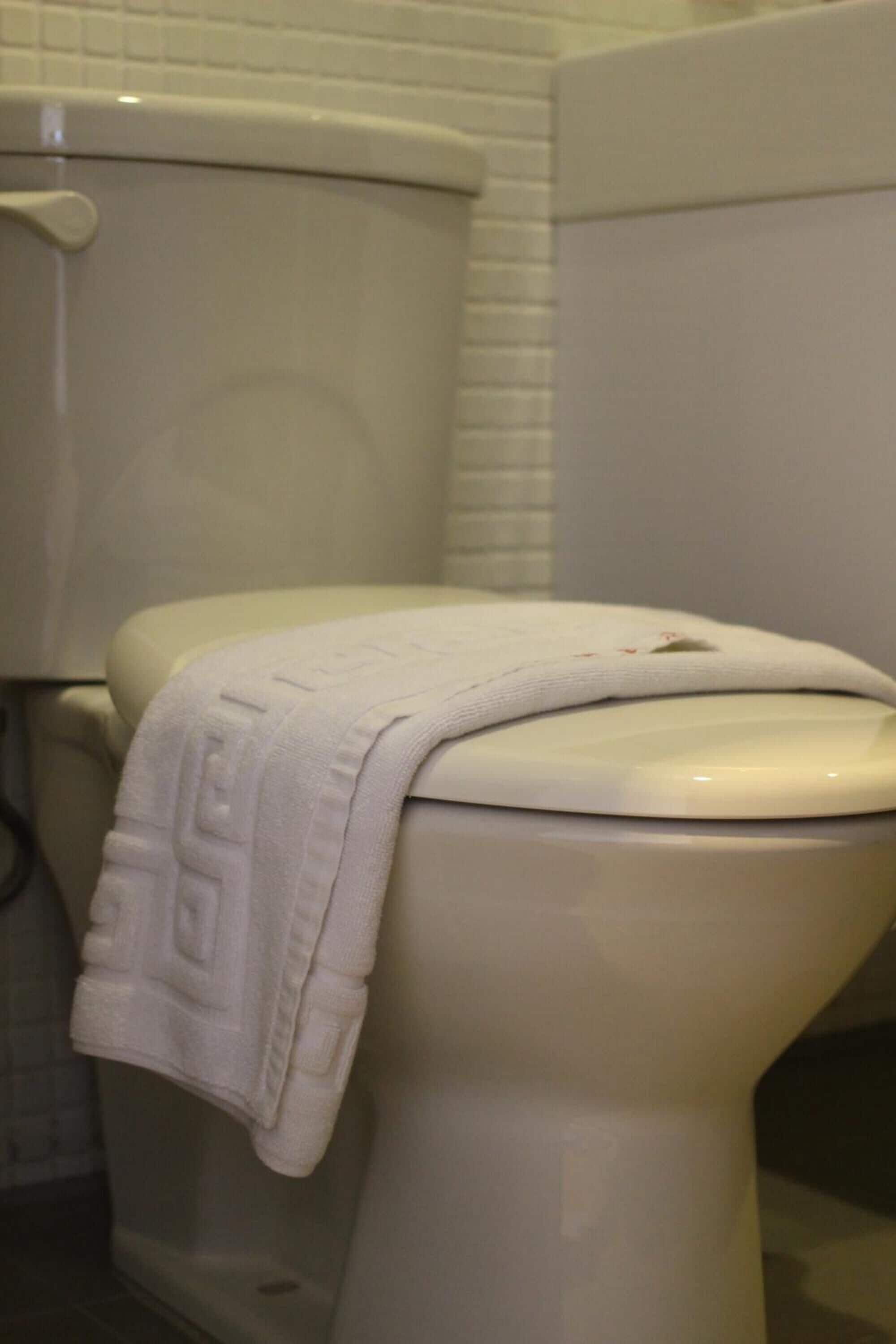 Un inodoro blanco con una toalla blanca sobre el asiento.
