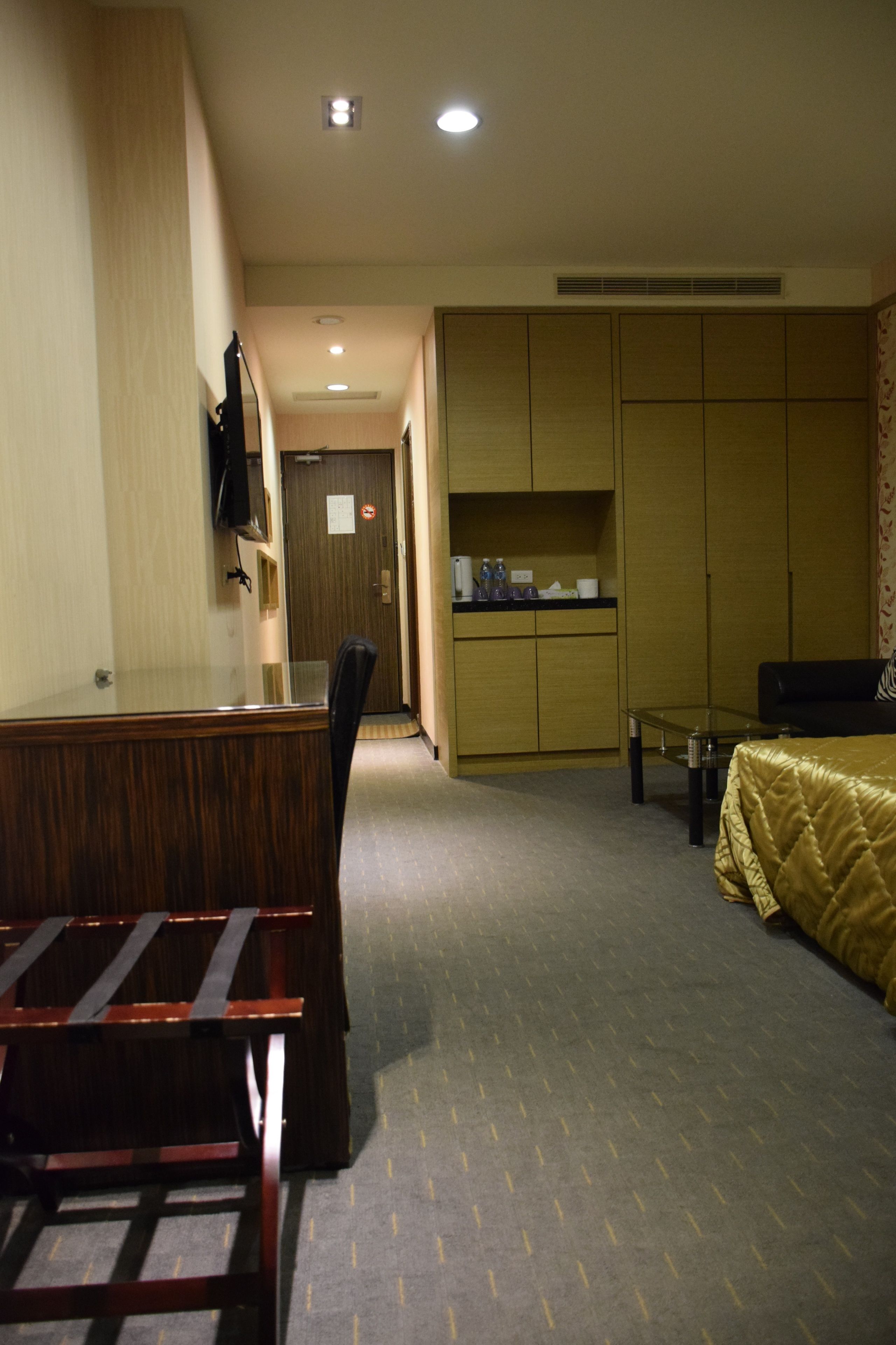 Une chambre d’hôtel comprenant un lit, un bureau, une chaise, une armoire et une petite table.